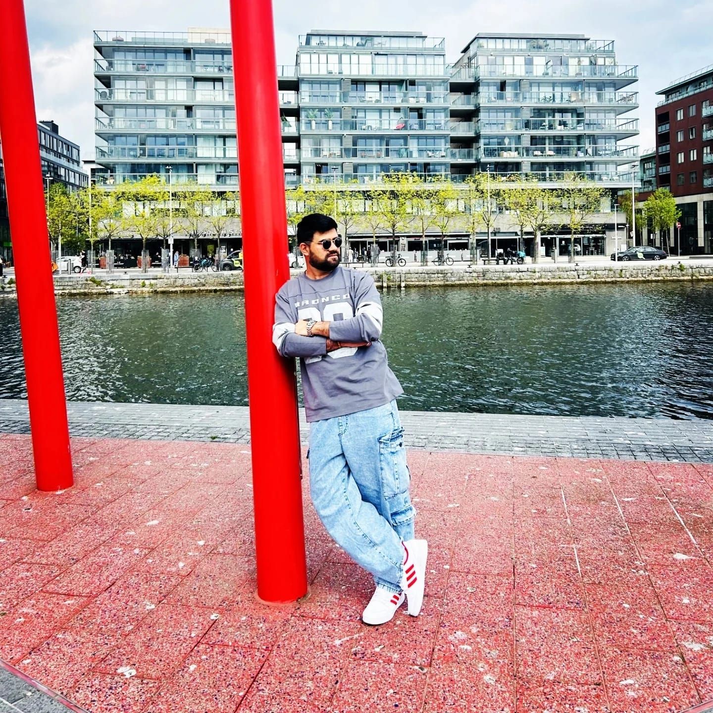 Malav Naik leaning on a red pole by the water in Dublin Docklands – I Built a Tested Data Pipeline for Dublin Bikes, for €0